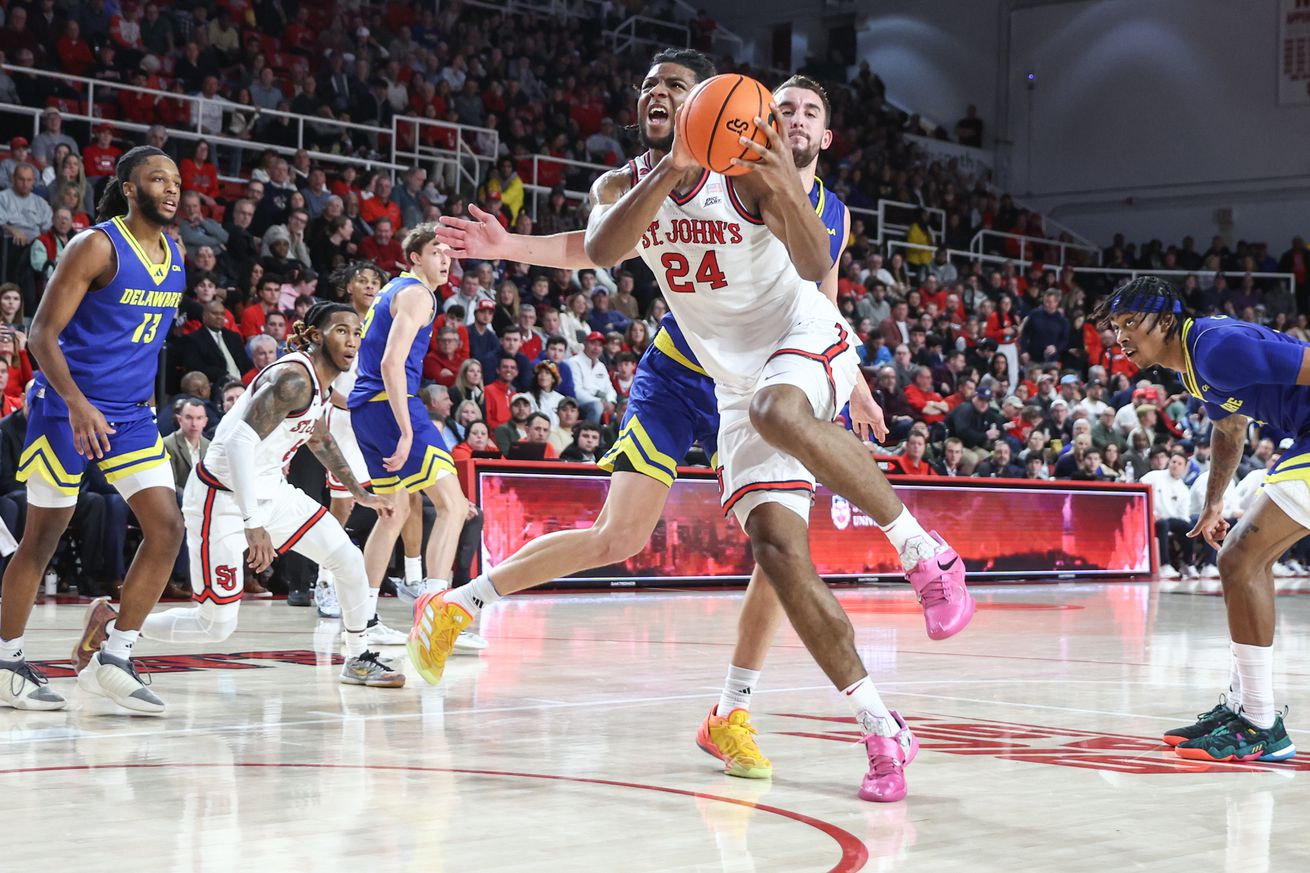 Dec 28, 2024; Queens, New York, USA; St. John’s Red Storm forward Zuby Ejiofor (24) drives past Delaware Fightin Blue Hens forward John Camden (2) in the second half at Carnesecca Arena. Mandatory Credit: Wendell Cruz-Imagn Images