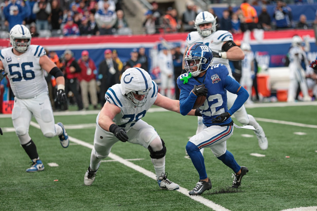 Dec 29, 2024; East Rutherford, New Jersey, USA; New York Giants cornerback Dru Phillips (22) returns an interception as Indianapolis Colts offensive tackle Bernhard Raimann (79) tackles during the second half at MetLife Stadium. Mandatory Credit: Vincent Carchietta-Imagn Images