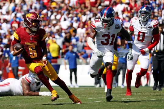 Sep 15, 2024; Landover, Maryland, USA; Washington Commanders quarterback Jayden Daniels (5) runs the ball against New York Giants safety Tyler Nubin (31) during the second quarter at Commanders Field. Mandatory Credit: Peter Casey-Imagn Images