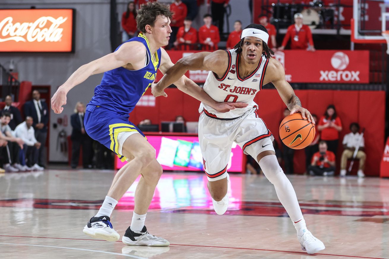 Dec 28, 2024; Queens, New York, USA; St. John’s Red Storm guard Aaron Scott (0) drives past Delaware Fightin Blue Hens forward Macon Emory (5) in the second half at Carnesecca Arena. Mandatory Credit: Wendell Cruz-Imagn Images