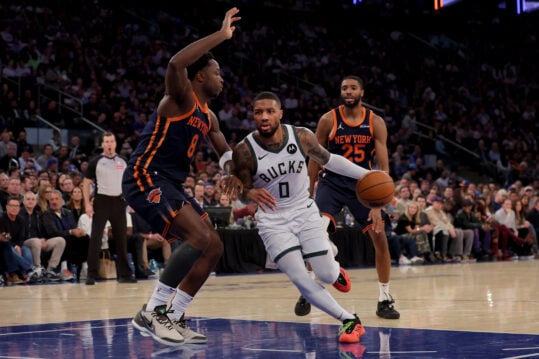 Nov 8, 2024; New York, New York, USA; Milwaukee Bucks guard Damian Lillard (0) drives to the basket against New York Knicks forwards OG Anunoby (8) and Mikal Bridges (25) during the second quarter at Madison Square Garden. Mandatory Credit: Brad Penner-Imagn Images